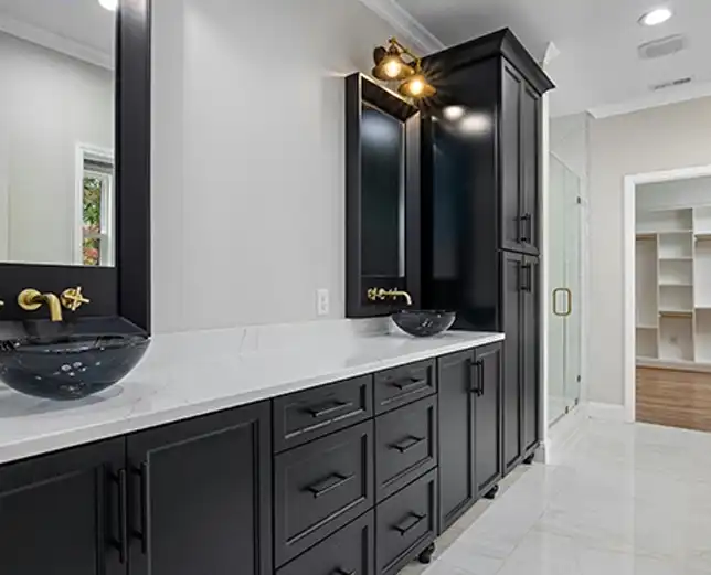 A bathroom with black cabinets and white counter tops.