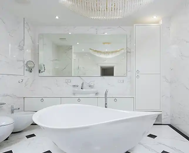 A white bathroom with a large mirror and bathtub.